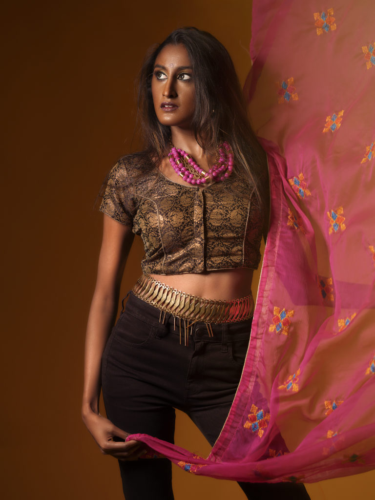 A portrait of a woman covered in accessories from designer Laruicci with a flowing scarf.
